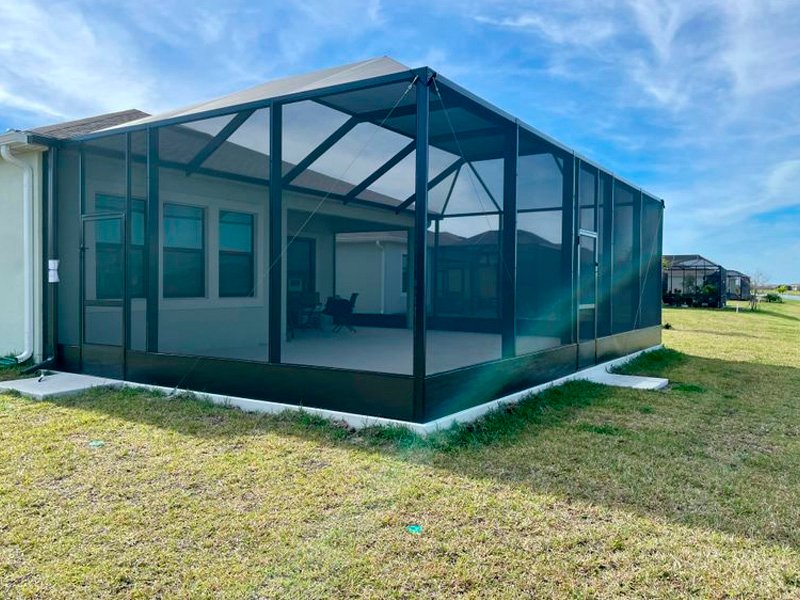 Black aluminum screened lanai enclosure installation in Clermont, FL residential backyard